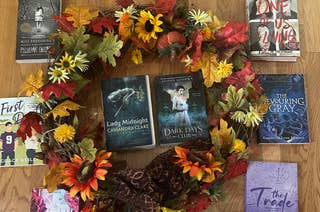 A circular arrangement of books with autumn-themed decorations, featuring titles like