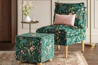 Floral upholstered chair and ottoman in a cozy room, with a small side table holding a vase of flowers