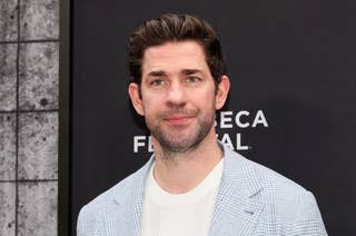 Man in a light checked suit and white shirt at a film festival event. Simple background with festival logo partially visible