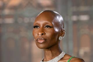 Person in a sleek green dress with feathered details and a sparkling necklace on a high-profile event