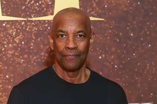 Denzel Washington in a black shirt standing in front of a glittery background