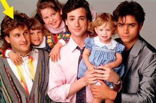Group photo of three men in suits and sweaters holding young children, posing closely together